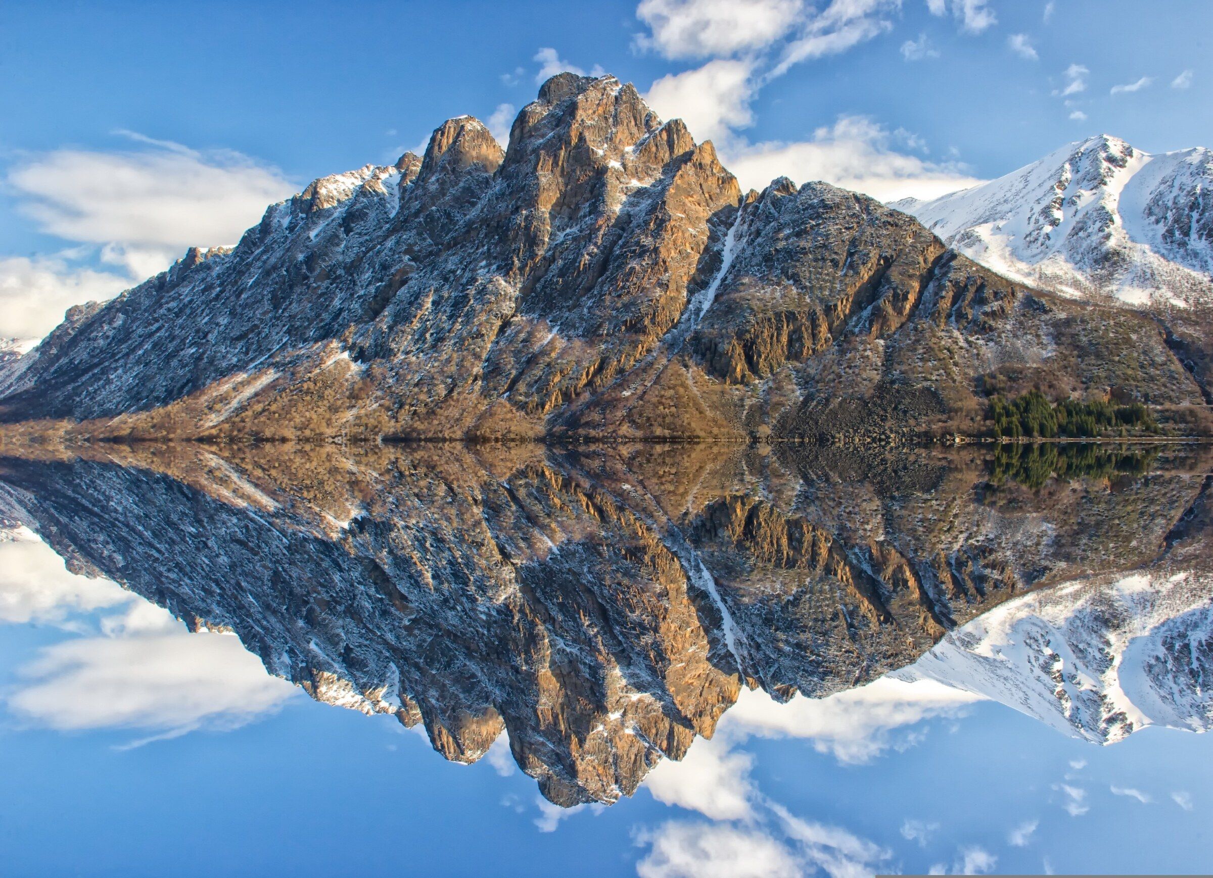 Snow-capped mountain peak reflected in a perfectly still lake