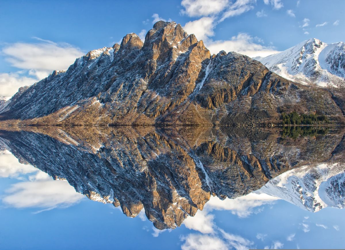 Snow-capped mountain peak reflected in a perfectly still lake